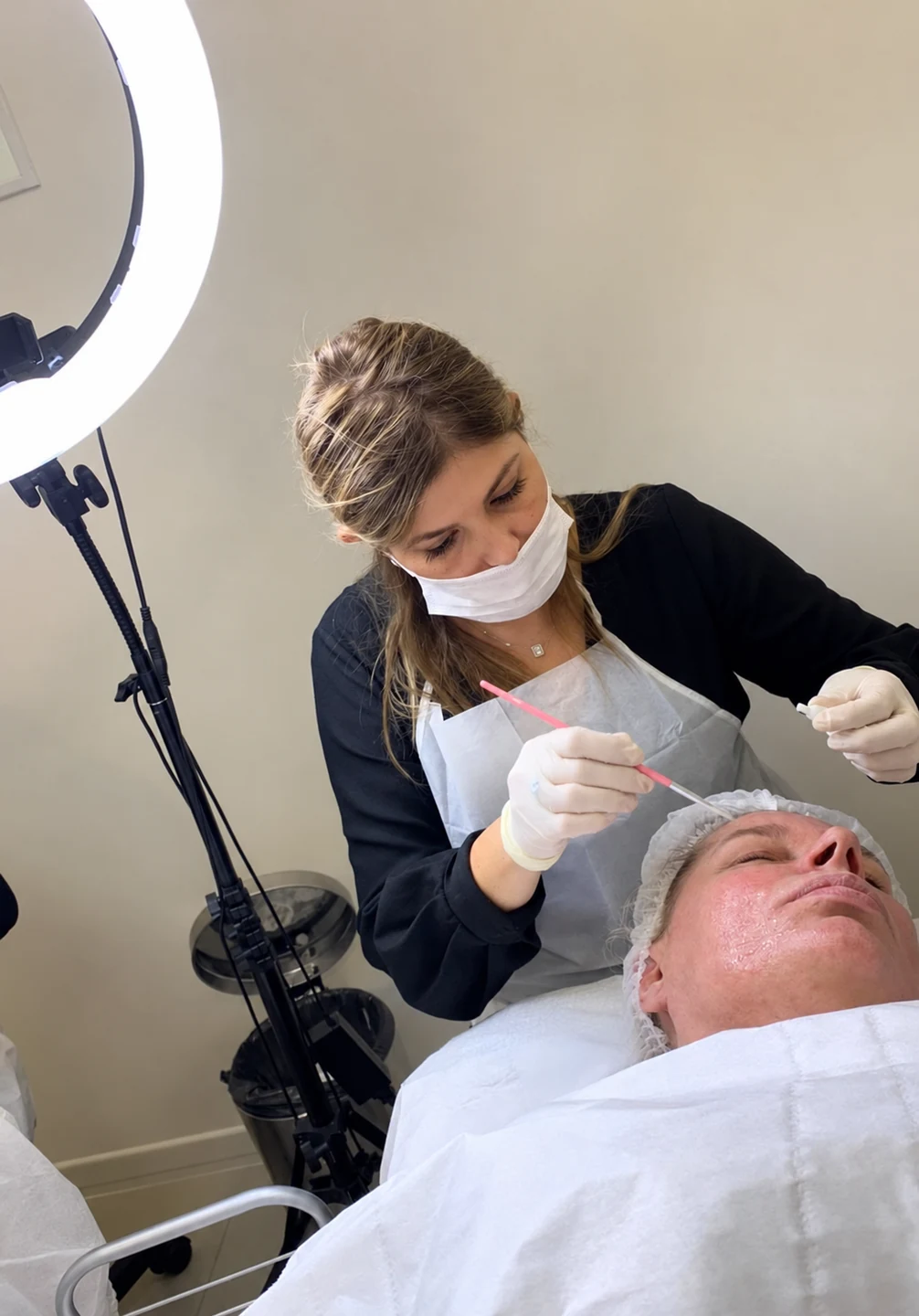 Une professionnelle de Pause Beauté applique un soin du visage sous une lampe annulaire